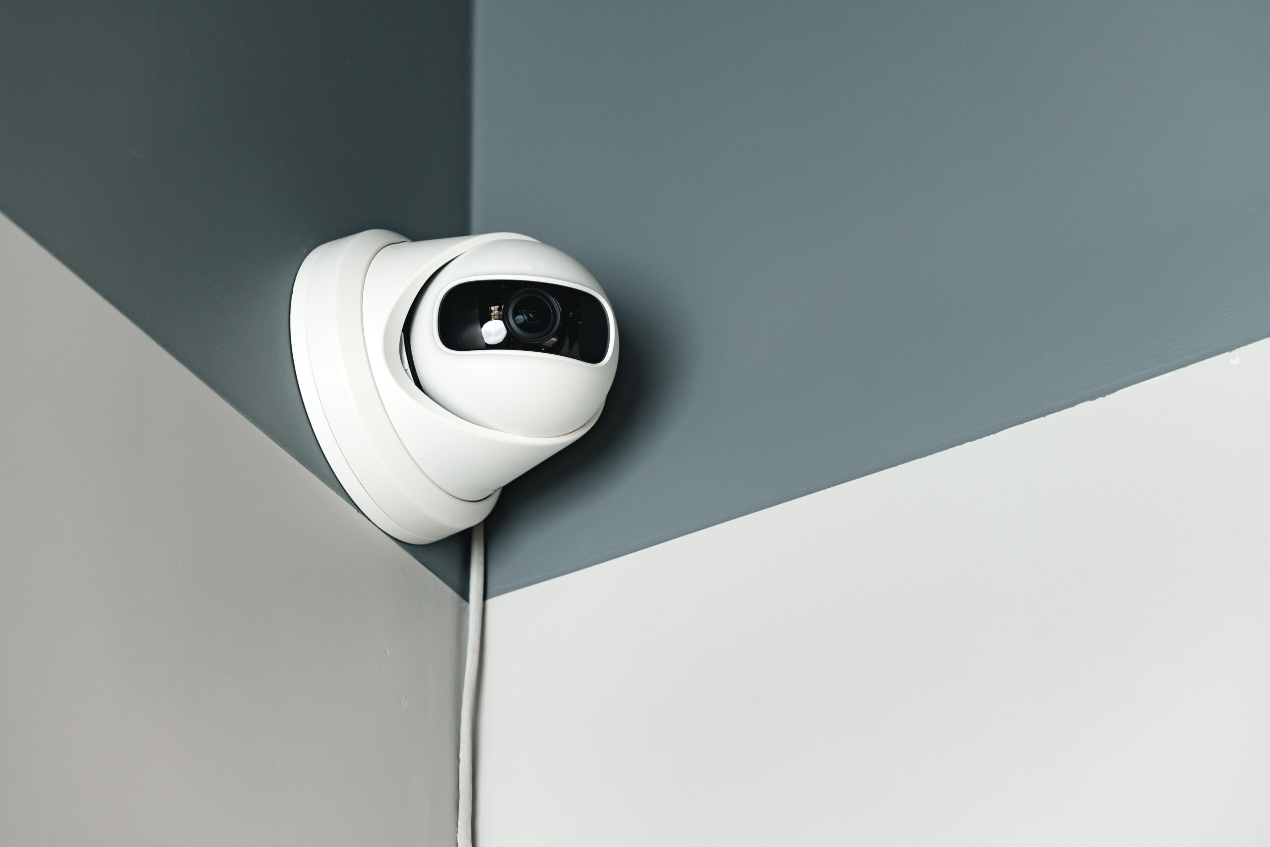 Turret CCTV camera on gray wall indoors close up